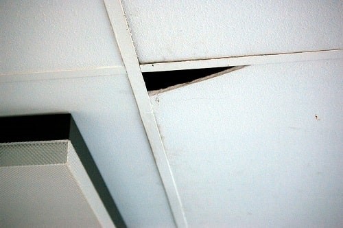 Broken ceiling tiles containing asbestos insulating board in a classroom. Any asbestos fibres would filter down into the classroom. From the report: Release of asbestos fibres in System Built Schools by Michael Lees, 2008.